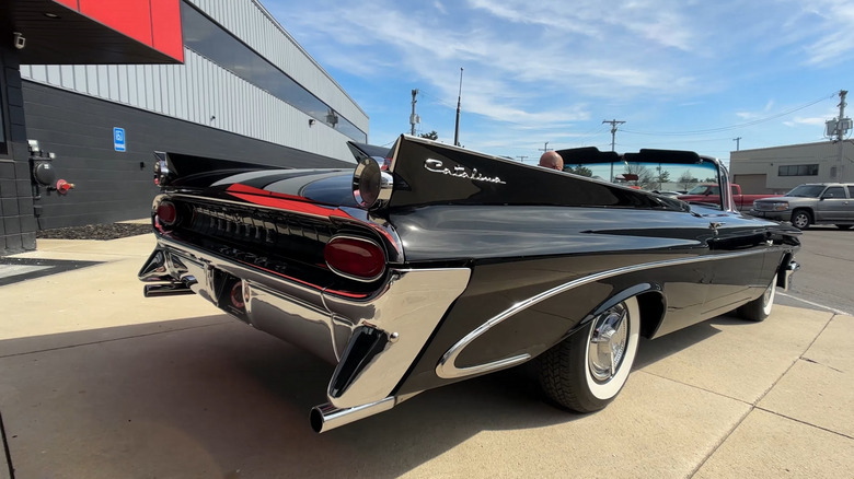 A beautiful black 1959 Pontiac Catalina Tri Power Convertible being driven in a suburban neighborhood