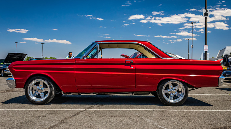 A red Ford Falcon Coupe from 1965 being displayed outdoors on pavement