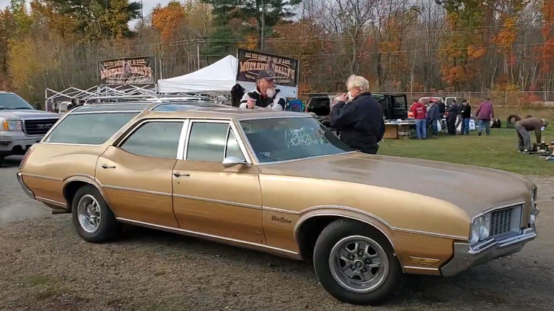 A golden 1968 Oldsmobile Vista Cruiser 455 seen parked at an auto show in the early evening, right side view visible.