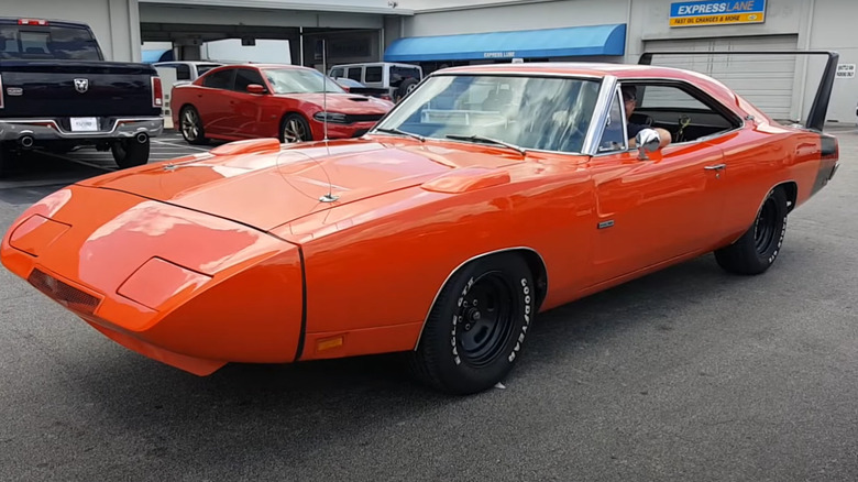A slamon orange 1969 Dodge Charger Daytona outside a garage, parked