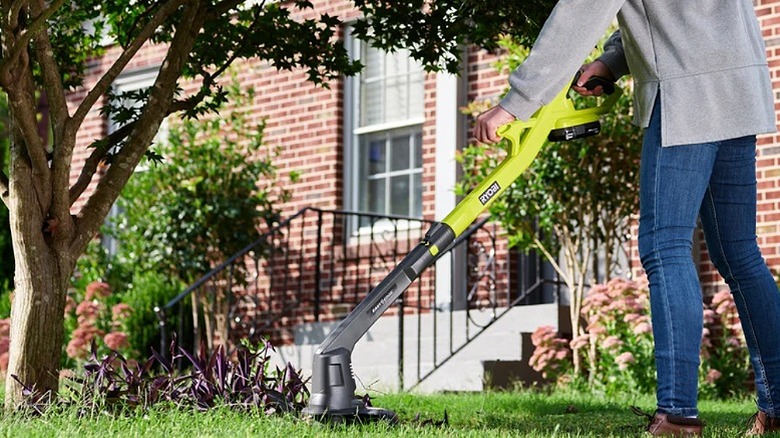 Using a string trimmer to cut overgrown grass.