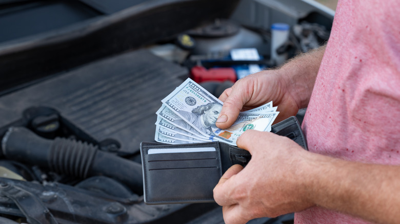 man holding cash over a car