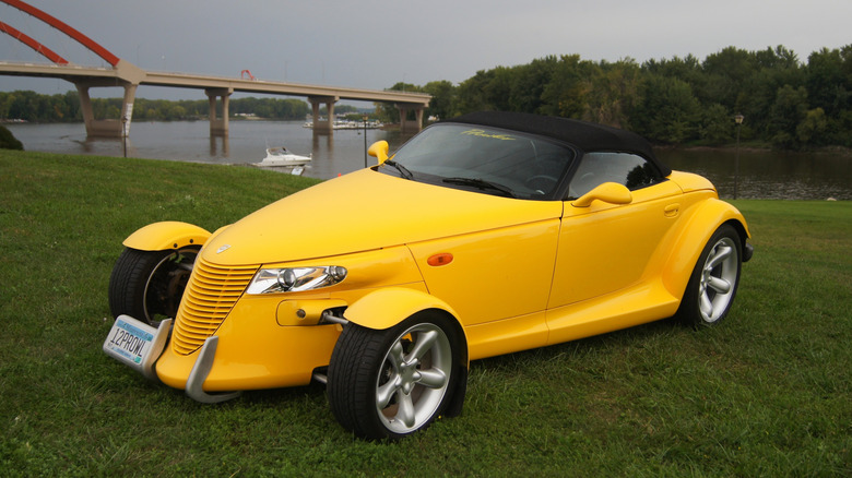Yellow 1999 Plymouth Prowler roadster seen from left front, parked on grass by a river