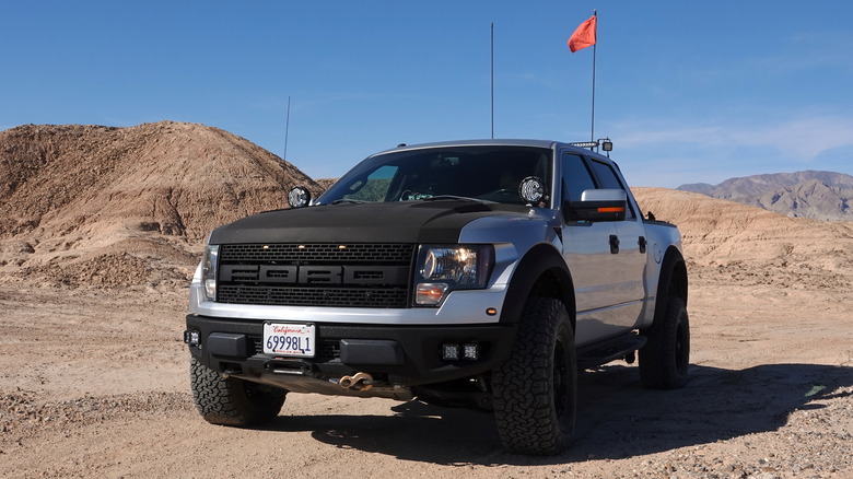 A modified first generation Ford F-150 Raptor in silver, front 3/4 view