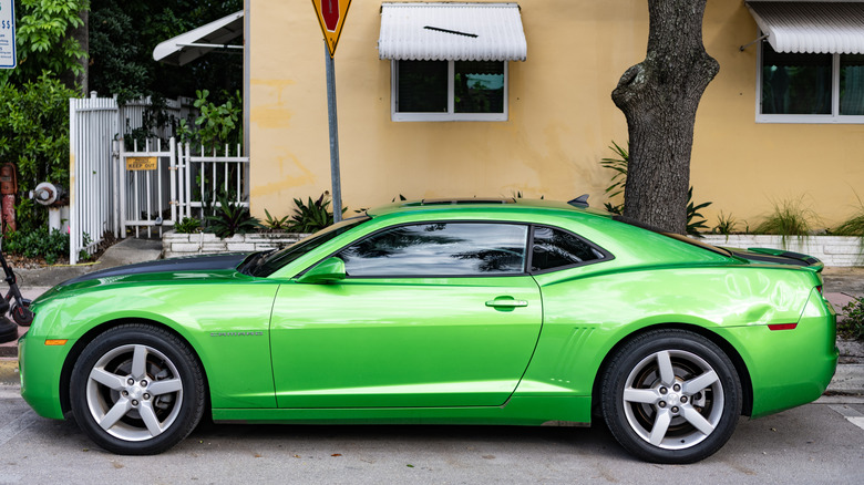 Green Chevrolet Camaro profile shot parked on street in front of building
