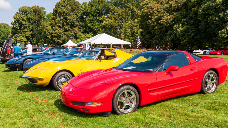 Multiple generation of Chevrolet Corvettes lined up on grass at auto show