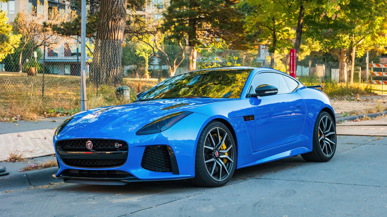 Blue Jaguar F-Type front 3/4 view parked on street in front of building