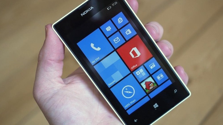 Hand holding Nokia Lumia 520 above a wood surface