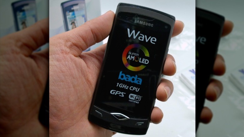 Hand holding Samsung Wave S8500 above a table