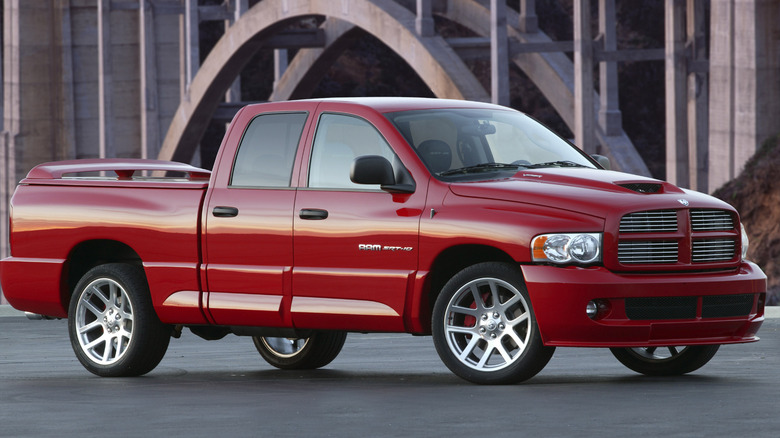 Red Dodge Ram SRT-10 parked on asphalt with a bridge in the background.