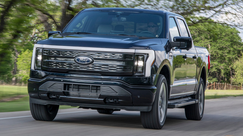 Black Ford F-150 Lightning driving on a rural road