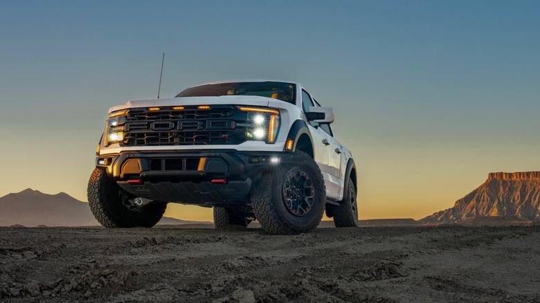 Low-angle photo of white Ford F-150 Raptor R parked in the desert at sunrise