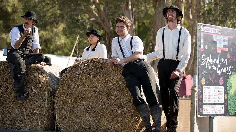 Amish men and a woman relaxing on hay bales