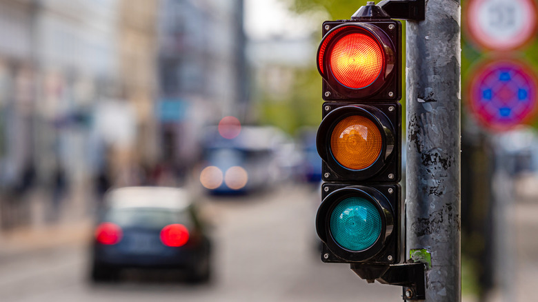 Red traffic light at an urban intersection with blurred cars in the background.