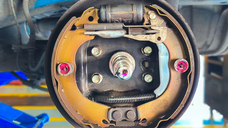 Close-up view of a car's drum brake assembly with exposed springs, wheel cylinder, and brake shoes.