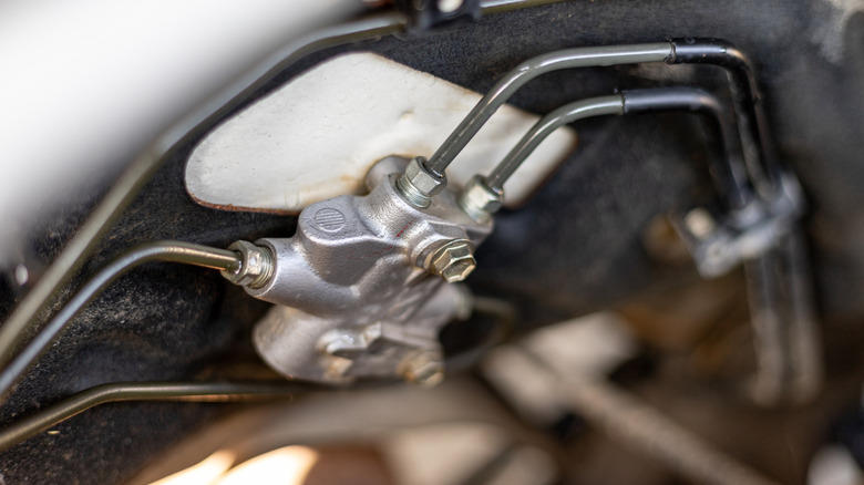 Close-up of a vehicle's brake proportioning valve and metal brake lines.