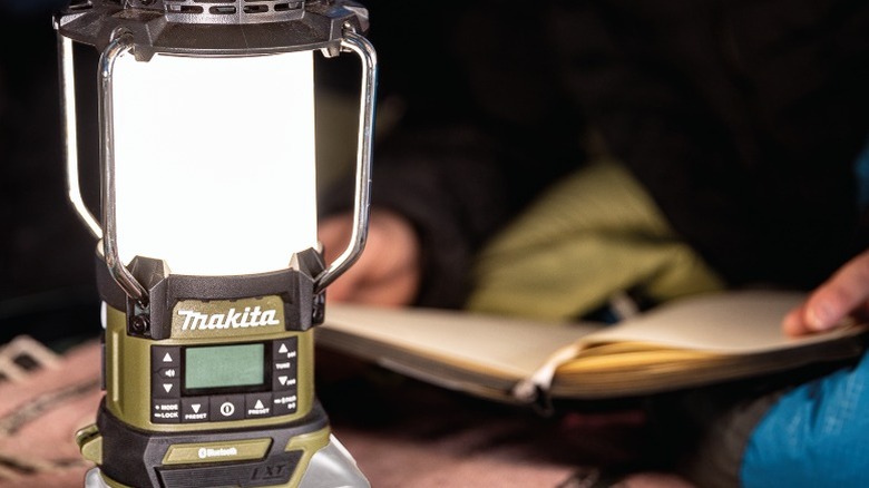 Makita Outdoor Adventure 18V LXT Bluetooth Radio and LED Lantern with a person reading in the background
