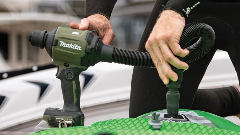 Person using a Makita Outdoor Adventure 18V LXT Brushless Cordless High Speed Blower/Inflator to inflate a dinghy