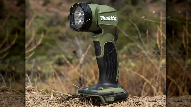 Makita Outdoor Adventure 18V LXT LED Flashlight standing upright on dirt