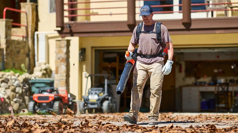 Contractor lowing leaves off a driveway with an Atlas 80V backpack blower