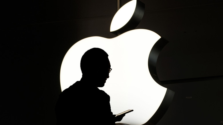 Steve Jobs looking at iphone in front of apple logo