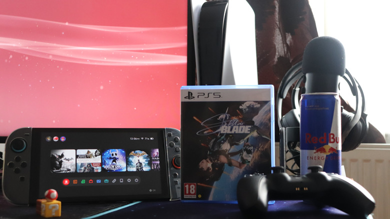 Modern gaming setup featuring a Nintendo Switch 2 console with visible game icons, a PlayStation 5 game case for "Stellar Blade," and a black PS5 controller.