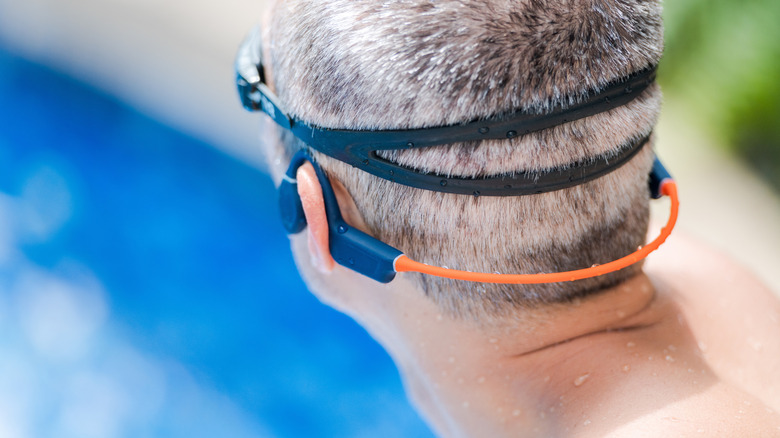 A man in a pool wearing swimming earbuds