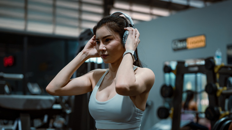 A woman putting on headphones at the gym.