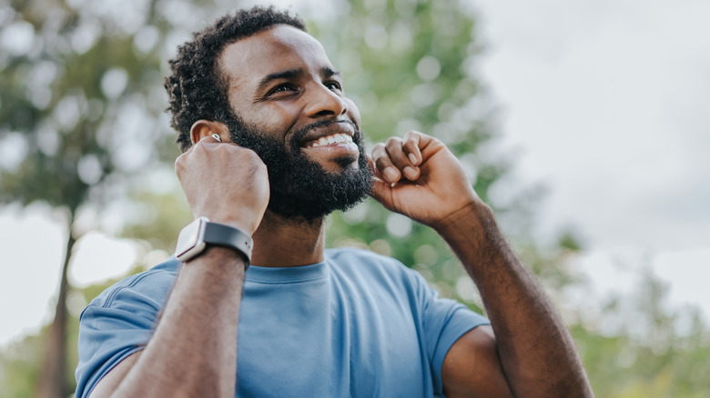 A man in exercise kit touching his earbuds.