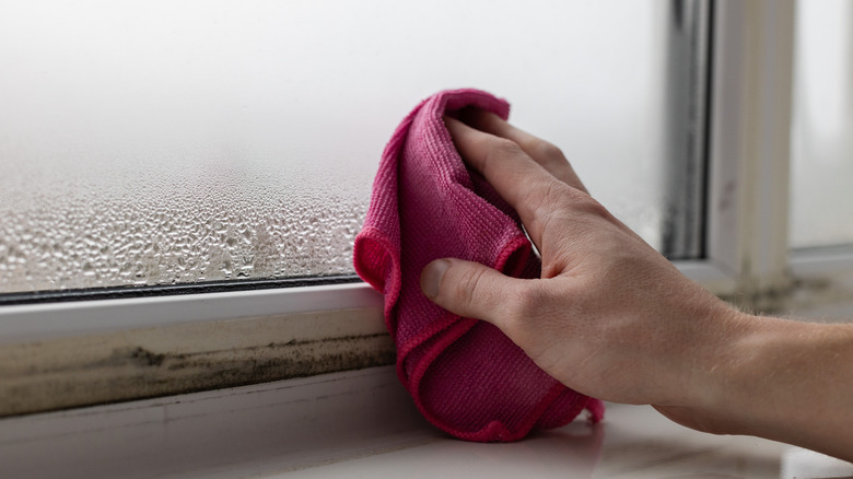 A person wiping down condensation with a cloth