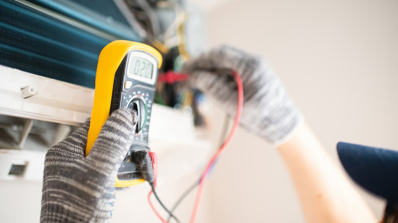 A technician measuring electric properties in an AC unit