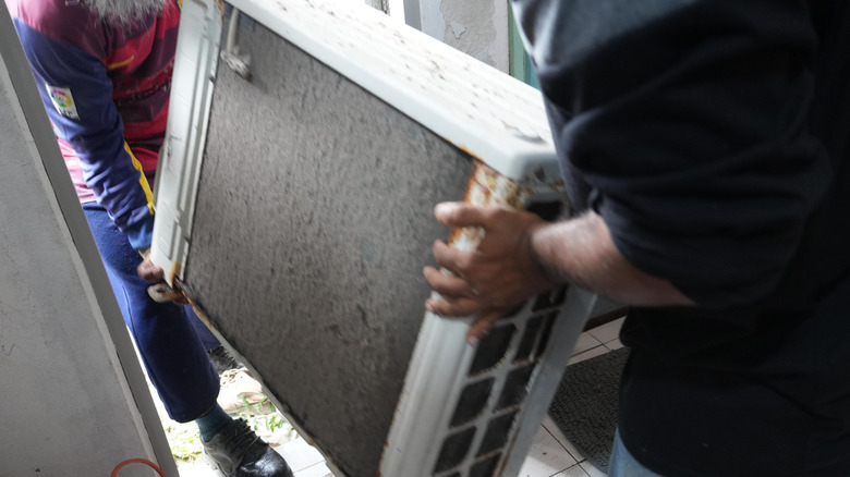Repair technicians carrying an old AC unit