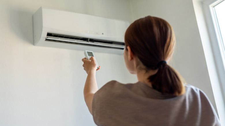 A person turning on an AC unit with a remote
