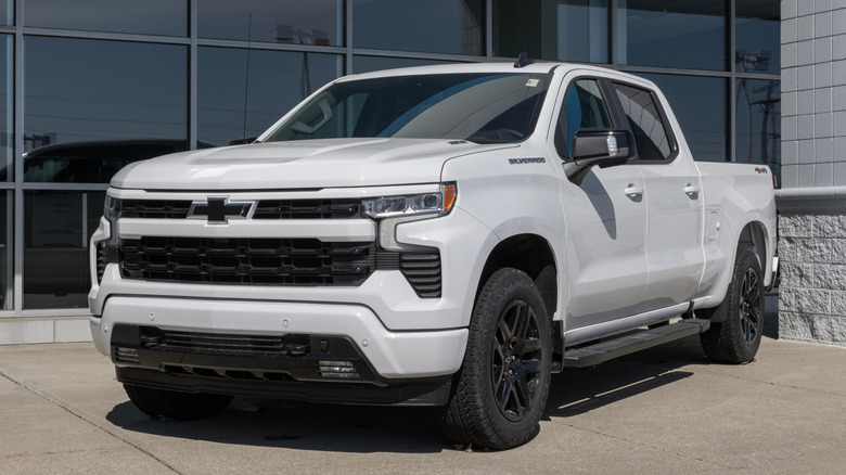 A white 2025 Chevrolet Silverado 1500 parked in front of a showroom