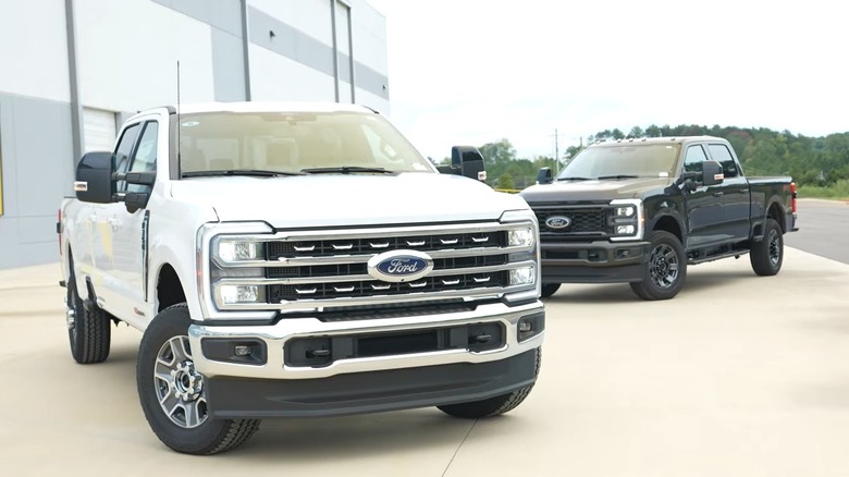 A white 2025 Ford F-250 Super Duty standing in front of a black 2025 Ford F-250 Super Duty