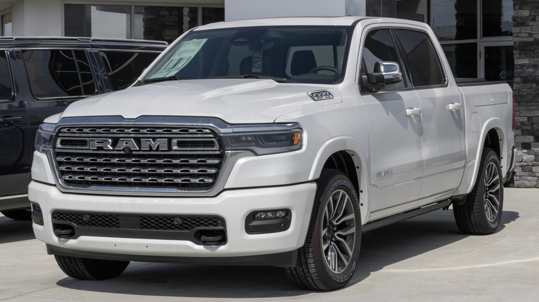 A white 2025 Ram 1500 parked in front of a showroom