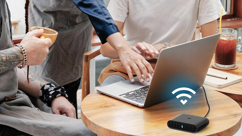 A travel router keeping a laptop connected in a cafe.