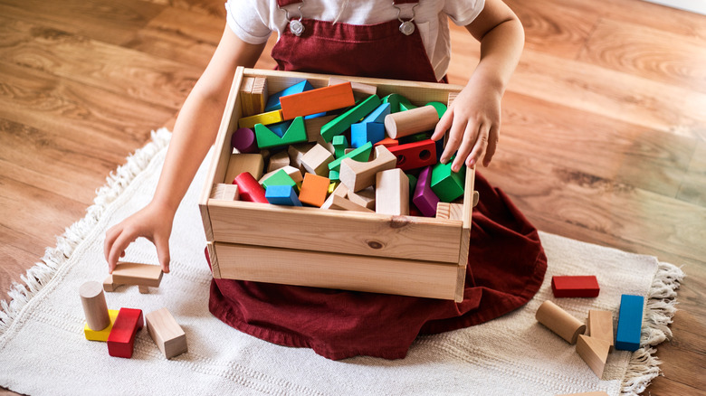child putting blocks in a crate-style box