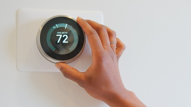a person adjusting a smart thermostat