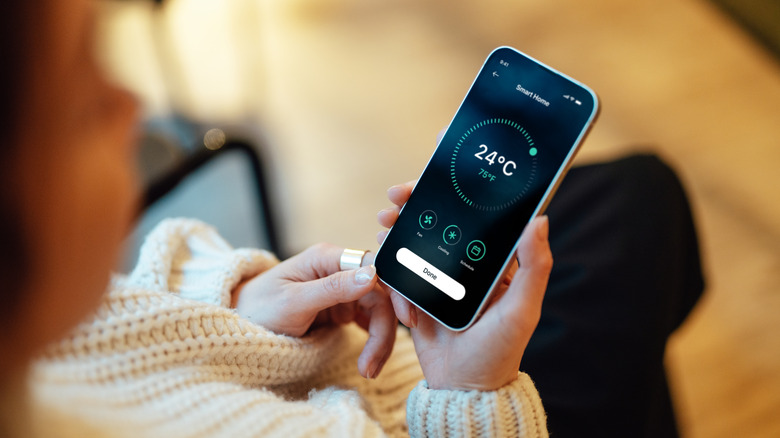 Woman changing the thermostat temperature using a phone