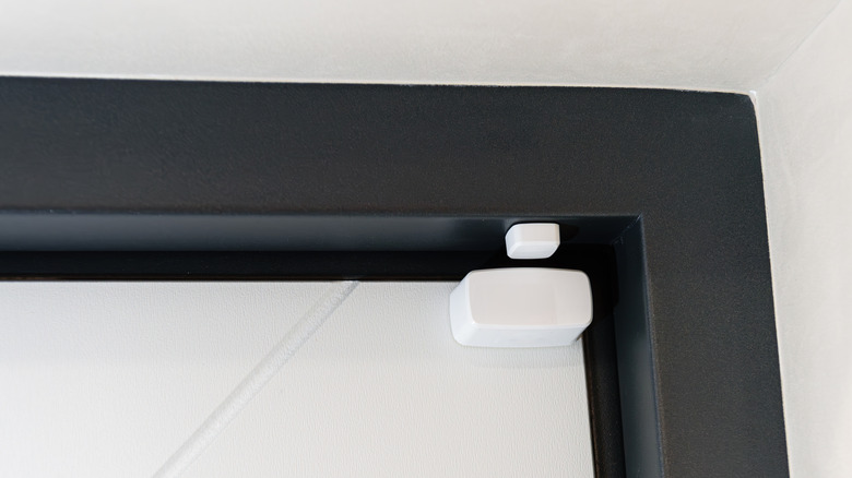 Small white window sensor in the top corner of the window frame