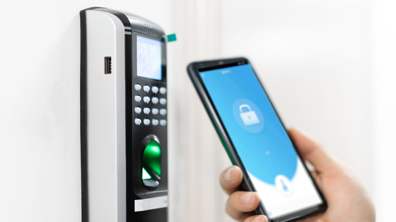 Hand holding a smartphone device near a programmable doorlock