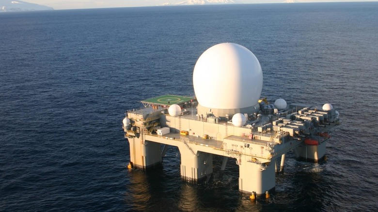 The SXB-1 ship seen on the ocean, sometime in the middle of the day with its huge radar domes visible prominently.