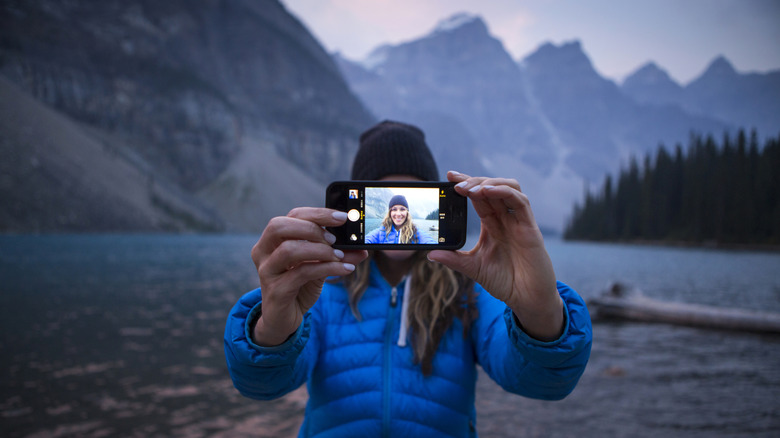 A woman taking a selfie next to a lake.