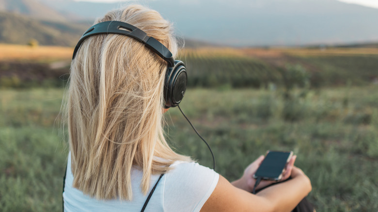 Woman listening to music on wired headphones.