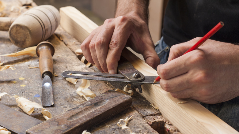 A carpenter taking measurement on a wooden piece