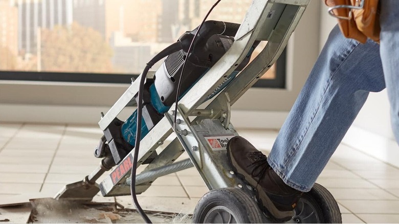 A person uses a Makita breaker mounted on a metal support