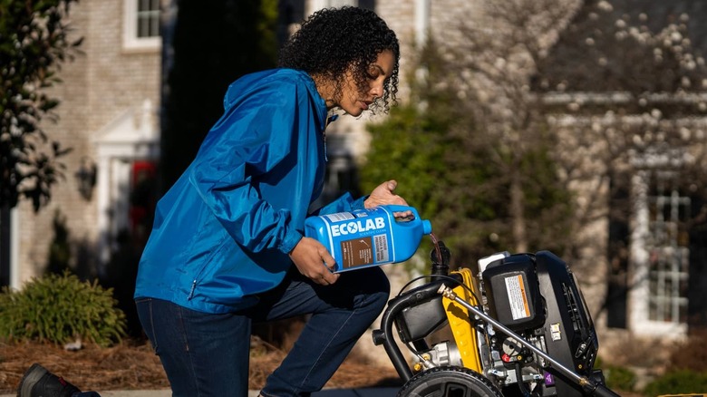 A woman refuels a pressure washer.