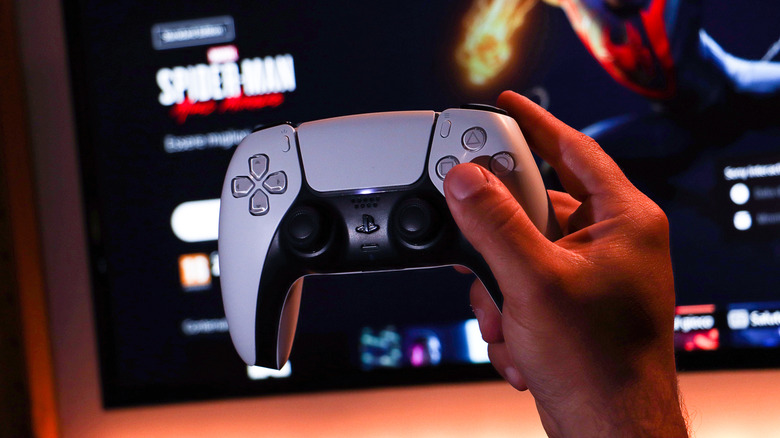 Holding the DualSense in front of a TV, which is showing "Marvel's Spider-Man"