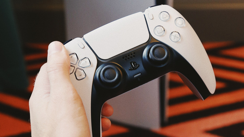 A person holding the DualSense controller in front of the PS5